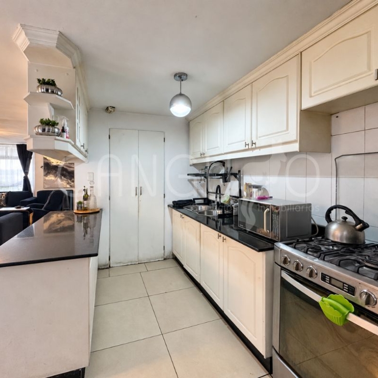 Cocina americana abierta con barra y muebles altos y bajos.